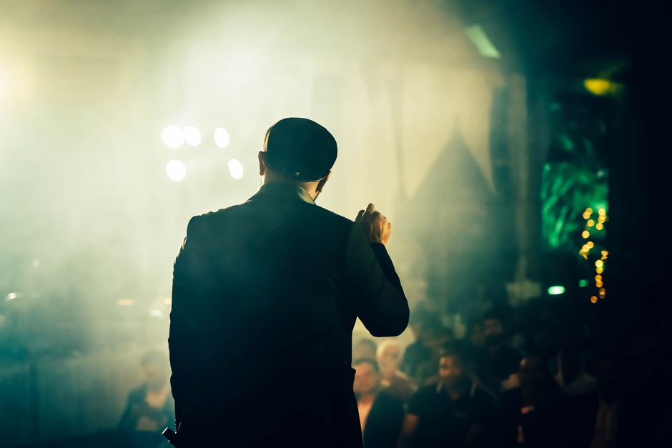 Muškarac se obraća publici u atmosferičnom noćnom klubu